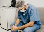 Tired male healthcare worker sitting with head down