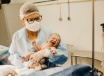 Midwife holding newborn baby in delivery room